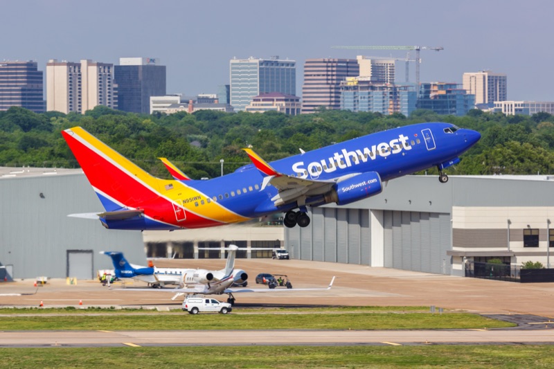 Southwest Airlines commercial aircraft taking off from Port San Antonio with city skyline in background