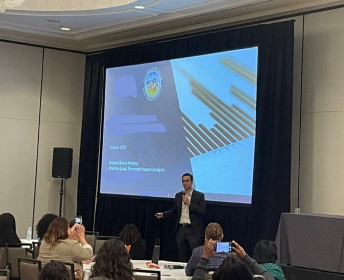 Samuel Maury-Holmes presenting economic impact analysis at an industry conference